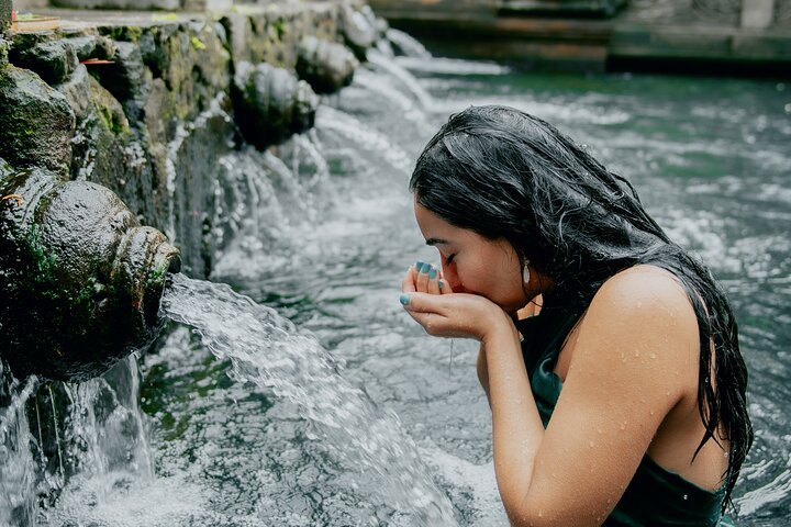 Woman participating in a traditional water purification ritual at Tirta Empul Temple in Ubud, Bali