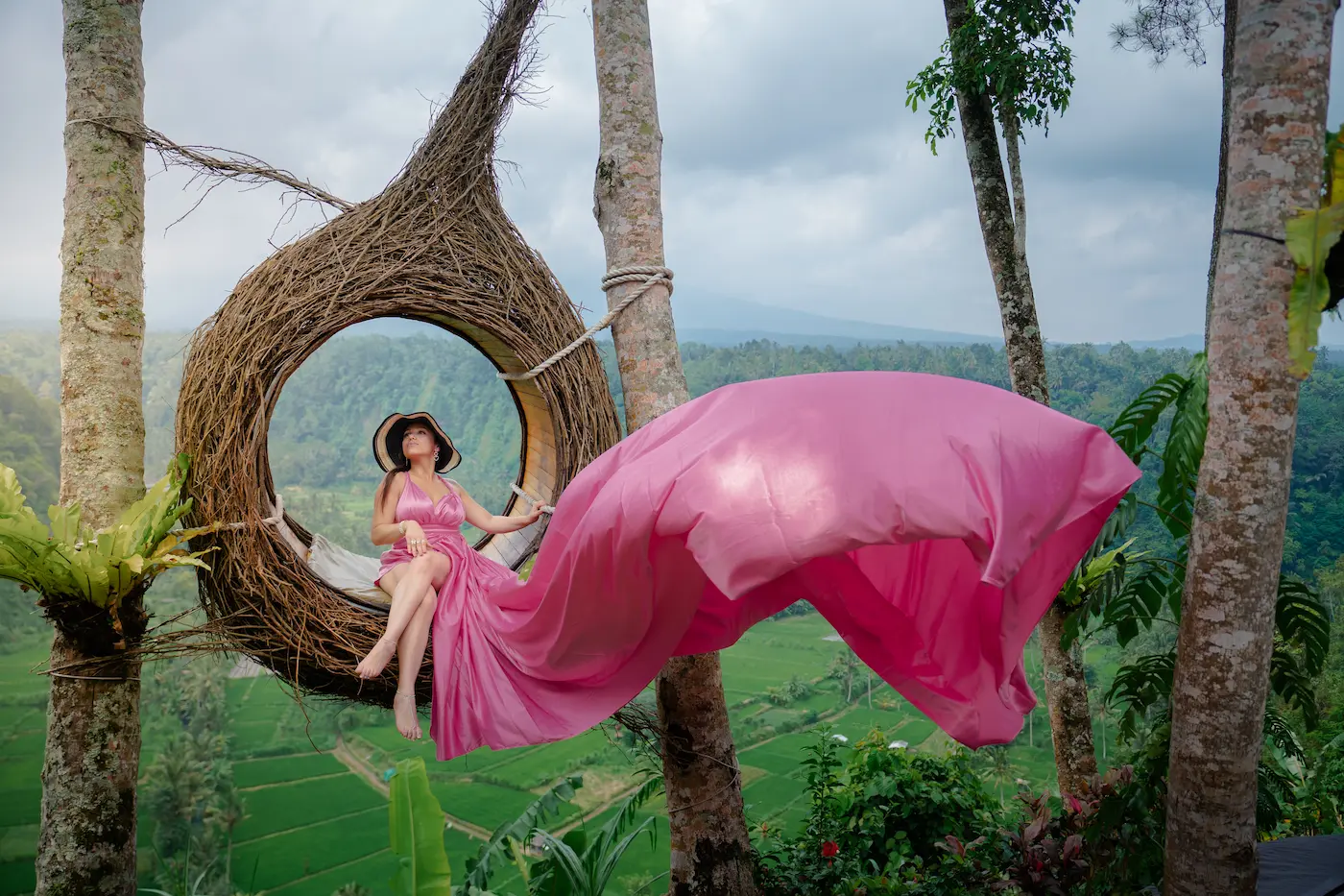 Female traveler posing in a hanging nest with flying dress – one of the top Bali Instagram spots