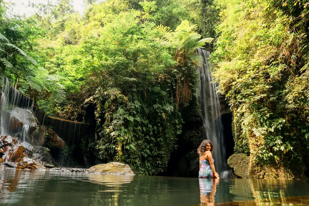 Traveler sitting in natural pools at Goa Raja Waterfall – hidden Instagrammable spot in Bali.