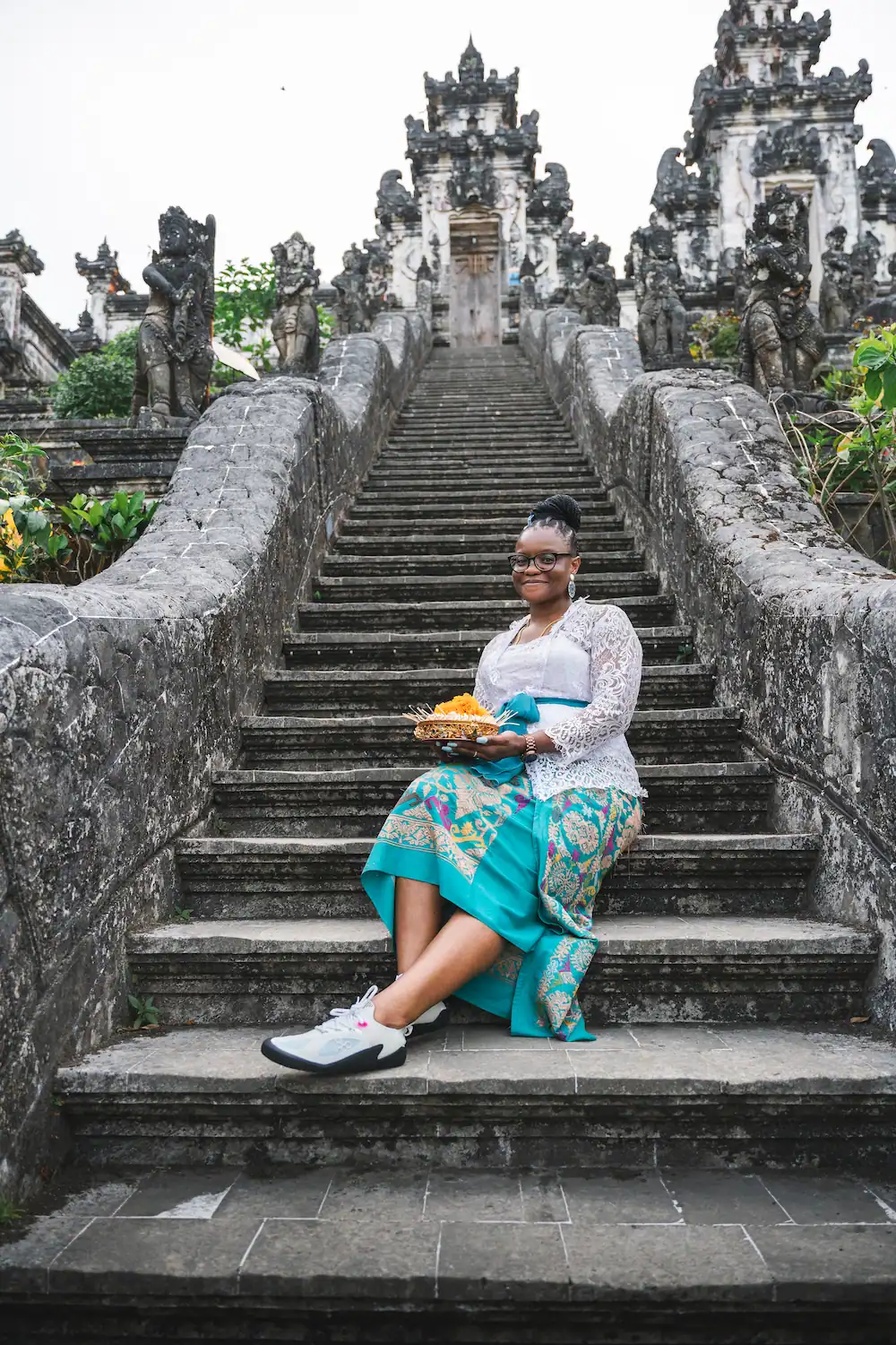 Tourist in Balinese attire sitting on the stairs of Lempuyang Temple, iconic photography spot on a Bali photography tour