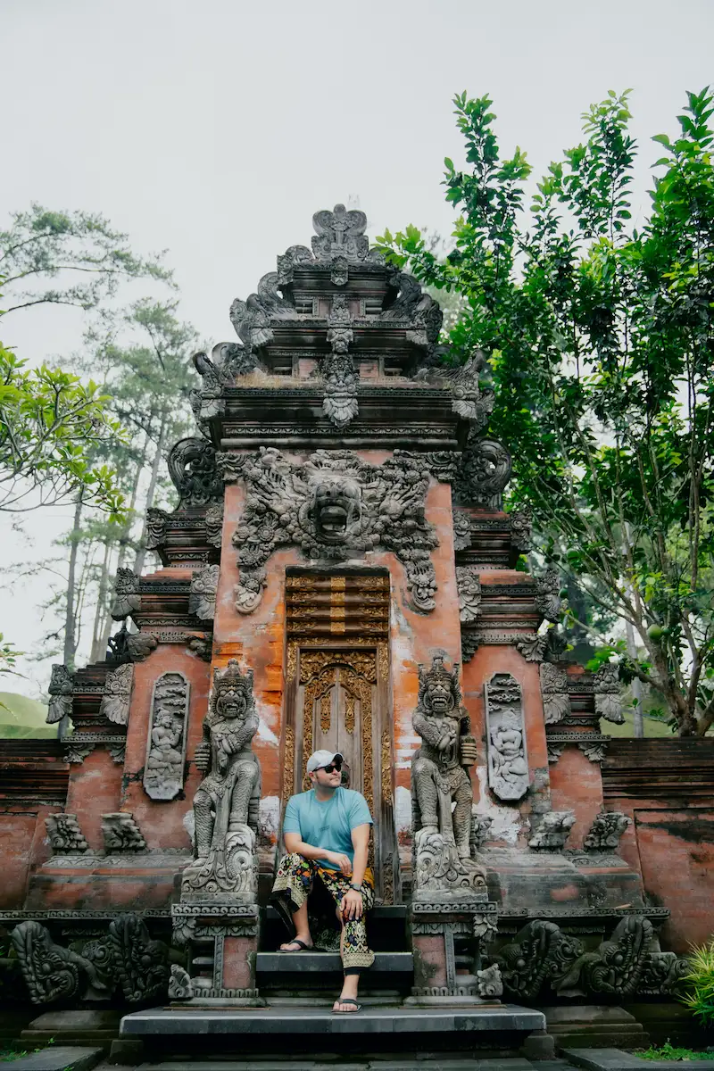 Traveler sitting at the iconic door of Tirta Empul, a sacred Ubud temple