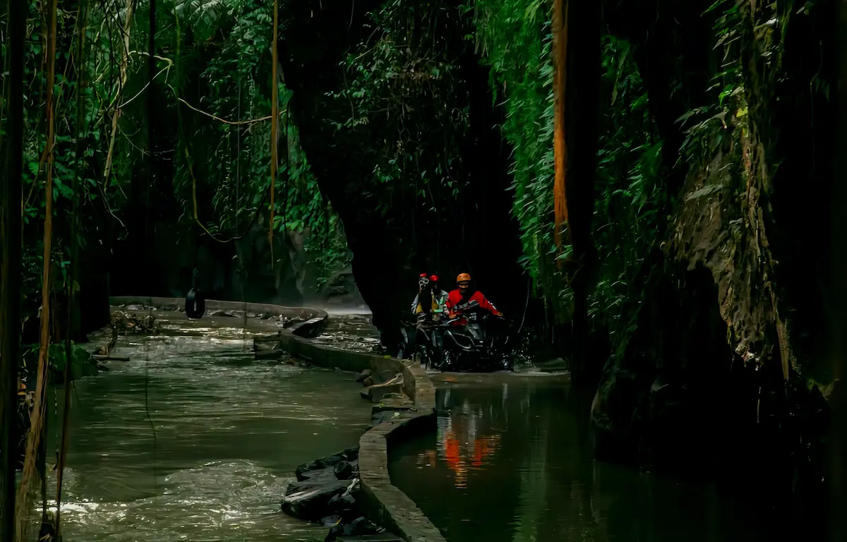 Rider crossing a river and passing a waterfall on a Bali ATV Tour in Ubud.