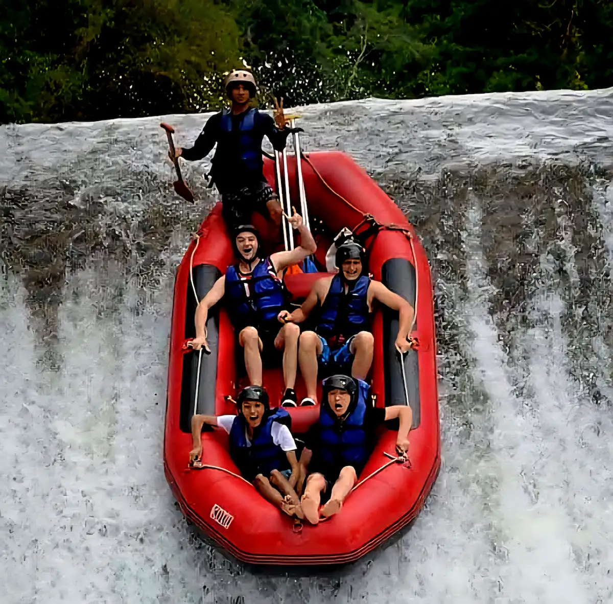 Adventurers sliding down a natural waterfall during an Ubud Rafting Tour on the Ayung River.