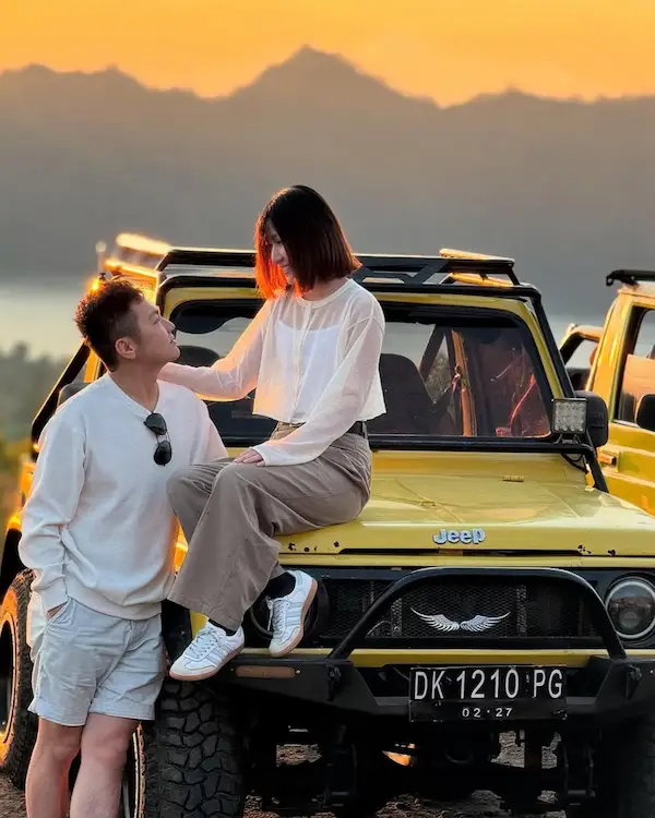 Couple sitting on jeep watching sunrise at Mount Batur, Bali.
