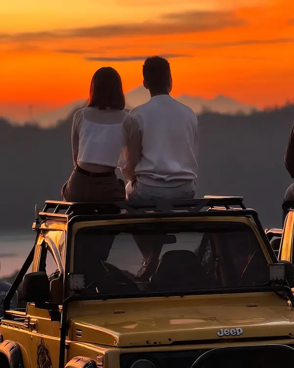 Couple enjoying sunrise on a jeep at Mount Batur, Bali.