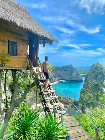 Man standing at Rumah Pohon Molenteng enjoying the stunning ocean view in Nusa Penida