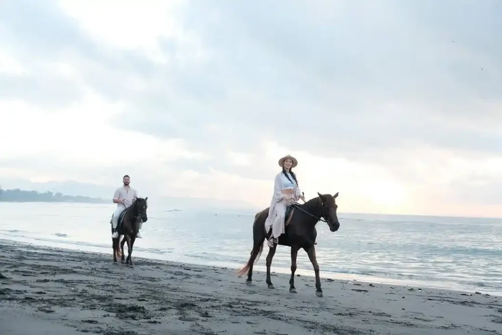 Couple enjoying a horse ride along a beautiful Bali beach.